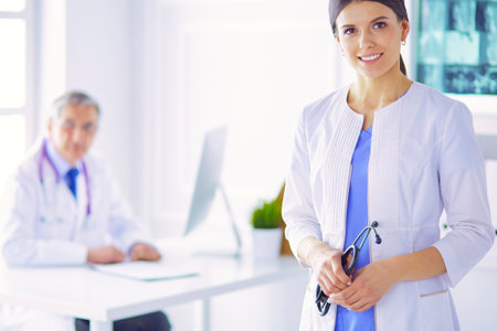 A doctor looking at the camera with her male colleage in the back of the conference room in hospitalの写真素材