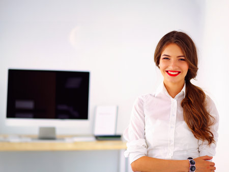Attractive businesswoman standing near wall in officeの写真素材