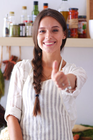 Young woman standing near desk in the kitchen. Young woman .の写真素材