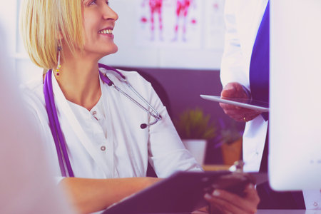 Female doctor sitting at table with laptop, workingの写真素材