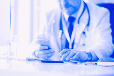 Portrait of senior doctor in office sitting at the deskの写真素材