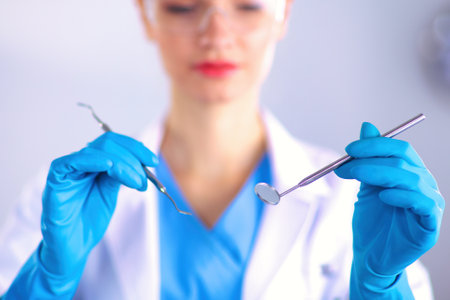 Attractive female dentist with tools , standing on grayの写真素材
