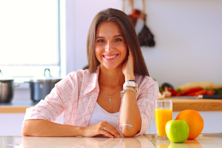 Young woman sitting a table in the kitchen. Young womanの写真素材