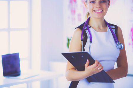Portrait of friendly female doctor with stethoscope and tablet in hands.の写真素材