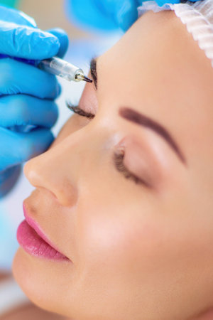 Permanent makeup for eyebrows. Closeup of beautiful woman with thick brows in beauty salonの写真素材