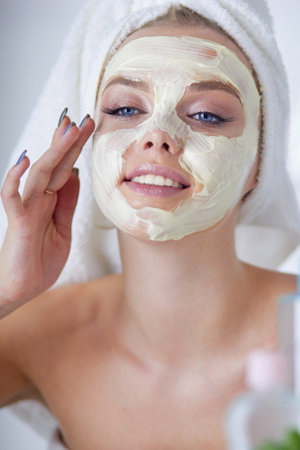 A picture of a young woman applying face powder in the bathroomの写真素材