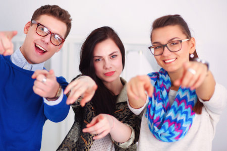 Young business people standing at office near desk and pointing youの写真素材