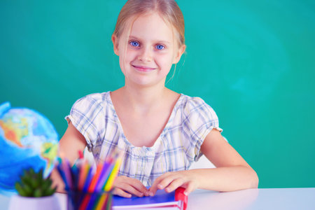 Girl studying at the desk, sitting on the desk.の写真素材