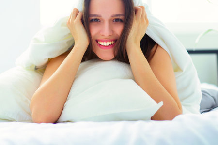 Pretty woman lying down on her bed at homeの写真素材