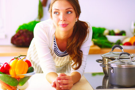 Young woman standing near desk in the kitchen. Young woman .の写真素材