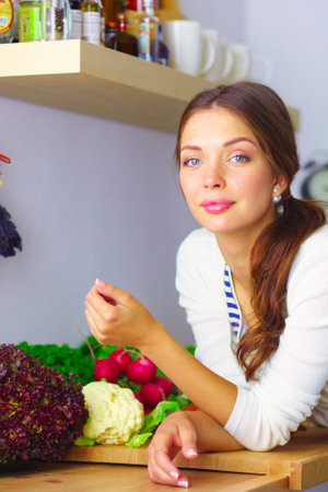 Young woman standing near desk in the kitchen. Young woman .の写真素材