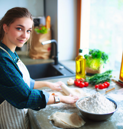 Portrait of young woman standing against kitchen background.の写真素材