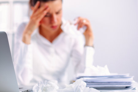 Stressed businesswoman sitting at desk in the officeの写真素材