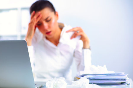 Portrait of tired young business woman with laptop computerの写真素材
