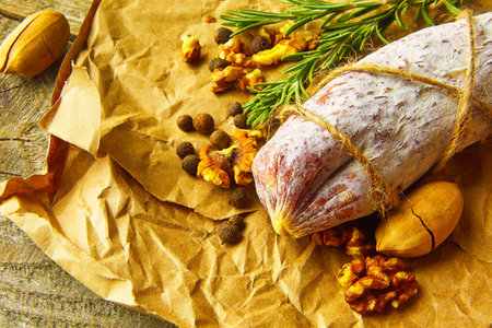 Italian salami wih sea salt, rosemary, garlic and nuts on paper. Rustic style. Top view.の写真素材