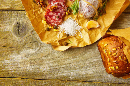 Italian salami wih sea salt, rosemary, garlic and nuts on paper. Rustic style. Close up.の写真素材