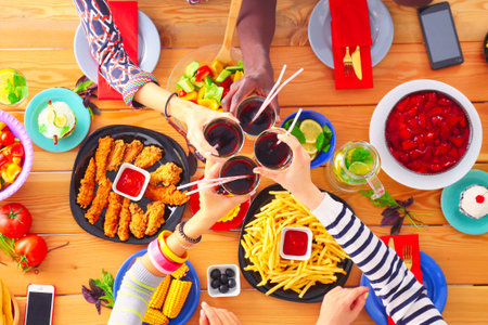Top view of group of people having dinner together while sitting at wooden table. Food on the table. People eat fast food.の写真素材