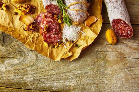 Italian salami wih sea salt, rosemary, garlic and nuts on paper. Rustic style. Close up.の写真素材