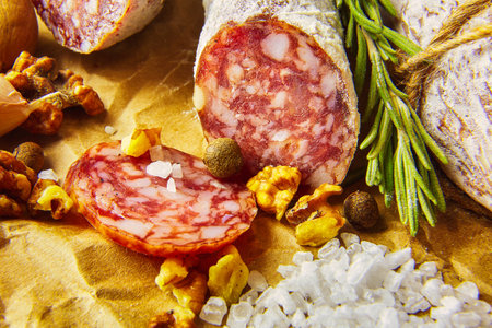 Italian salami wih sea salt, rosemary, garlic and nuts on paper. Rustic style. Close up.の写真素材