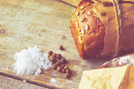 Two Loaves of Bread packed in paper on wooden table with salt and papper. Cropped photo.の写真素材