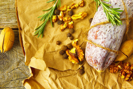 Italian salami wih sea salt, rosemary, garlic and nuts on paper. Rustic style. Top view.の写真素材