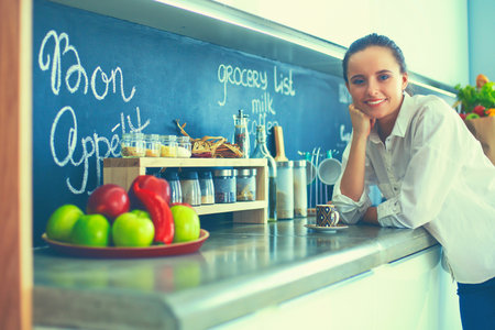 Portrait of young woman standing against kitchen backgroundの写真素材