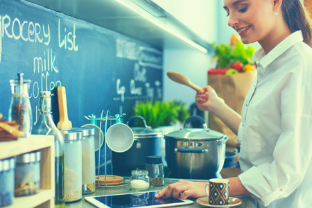 Young woman standing by the stove in the kitchenの写真素材