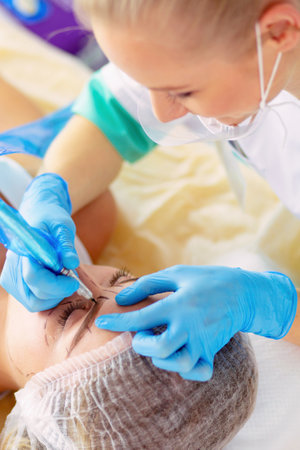 Permanent makeup for eyebrows. Closeup of beautiful woman with thick brows in beauty salon.の写真素材