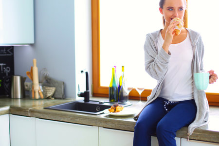 Beautiful young woman using a digital tablet in the kitchen.の写真素材