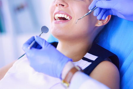 Young Female patient with open mouth examining dental inspection at dentist office.の写真素材