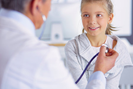 Girl and doctor with stethoscope listening to heartbeatの写真素材