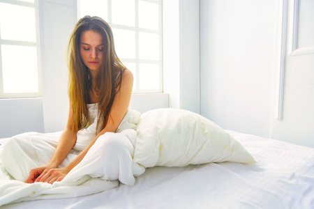 Young female feeling pain in bed.の写真素材