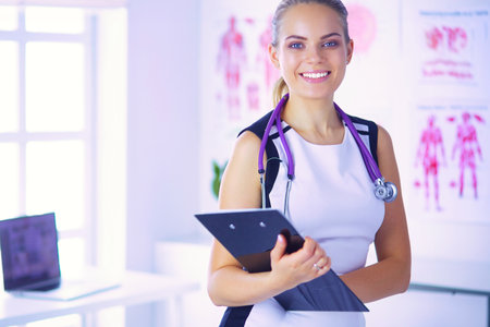 Portrait of friendly female doctor with stethoscope and tablet in hands.の写真素材