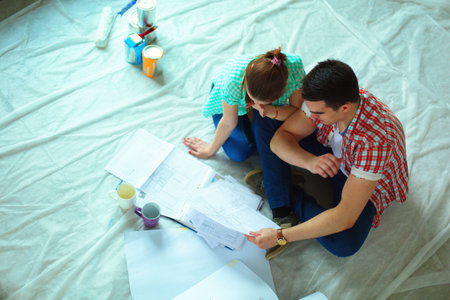 Young couple sitting on floor and calculating about they savingsの写真素材