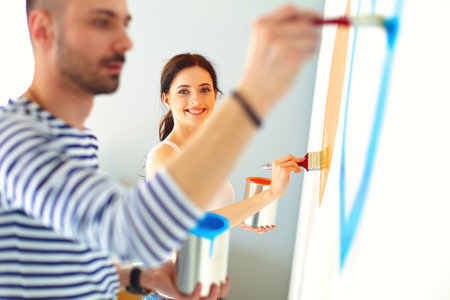 Portrait of happy smiling young couple painting interior wall of new houseの写真素材