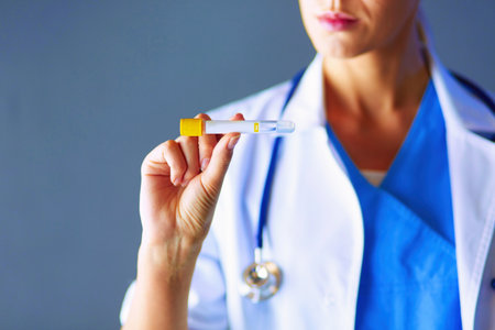 Female medical or research scientist or doctor using looking at a test tube of clear solution in a lab or laboratory.の写真素材
