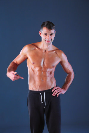 muscular man. Muscular man on a grey background showing muscles. Fitness instructor. Fitness professional. Workout. Mens fitness.の写真素材