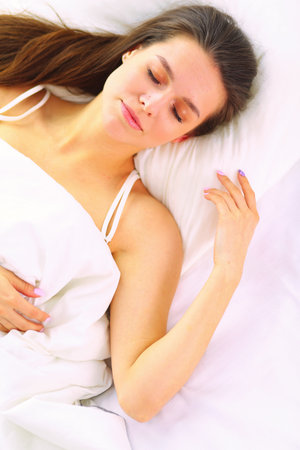 Pretty woman lying down on her bed at homeの写真素材