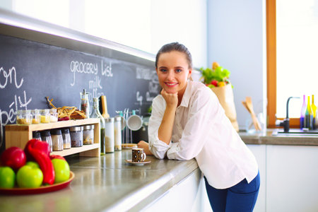 Portrait of young woman standing against kitchen background.の写真素材