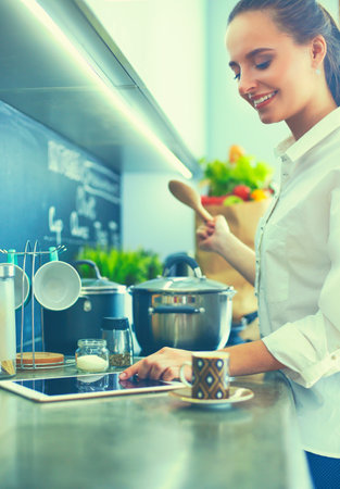 Young woman standing by the stove in the kitchenの写真素材