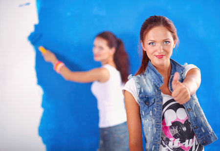 Two Young beautiful women holding color palette , standing near wall. Two Young beautiful womenの写真素材