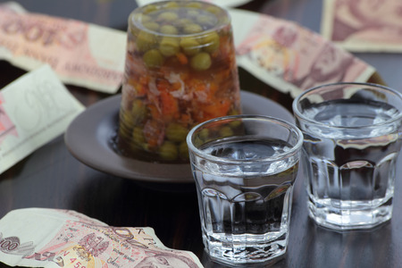 Closeup of two shots of vodka, pork leg aspic and old polish zloty notes.の写真素材