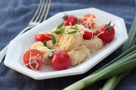 Gnocchi with tomatoes and grated cheese on a blue plate.の写真素材