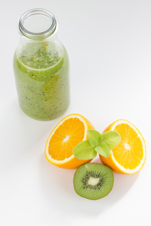 Kiwi and orange juice in glass bottles isolated on white.の写真素材