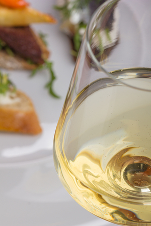Glass of white wine and tartines with meat and veggies.の写真素材
