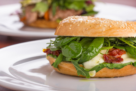Bagel with melted cheese and green salad served on a white plate.の写真素材