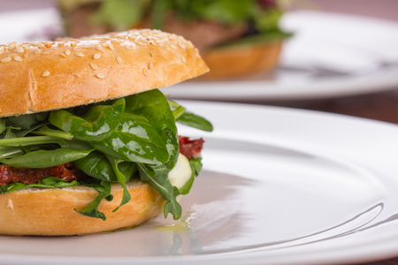 Bagel with melted cheese and green salad served on a white plate.の写真素材