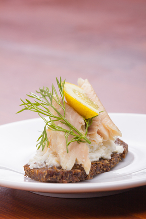 Smoed trout tartine with a slice of lemon and piece of dill.の写真素材