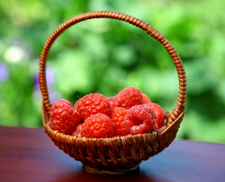 Basket of red raspberries on green backgroundの写真素材