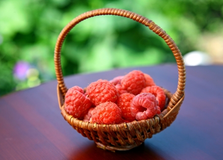 Full basket of red raspberries on the tableの写真素材